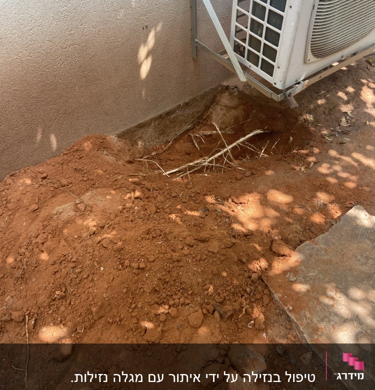 אדמה חפורה ליד קיר עם יחידת מיזוג אוויר